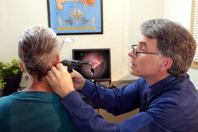 man examening ear with otoscope